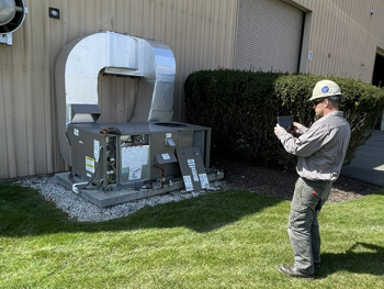 Worker taking a picture of outside HVAC system